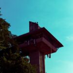 brown tall tower near tree during daytime